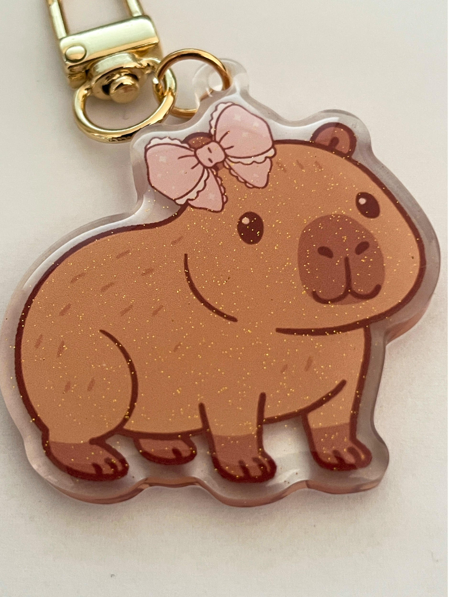 Keychain with a bear design wearing a pink bow on a light background