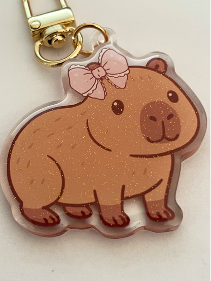 Keychain with a bear design wearing a pink bow on a light background