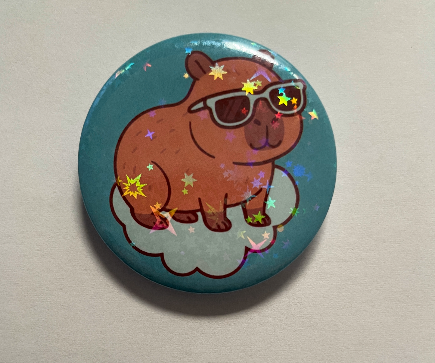Button badge with a cartoon capybara wearing sunglasses