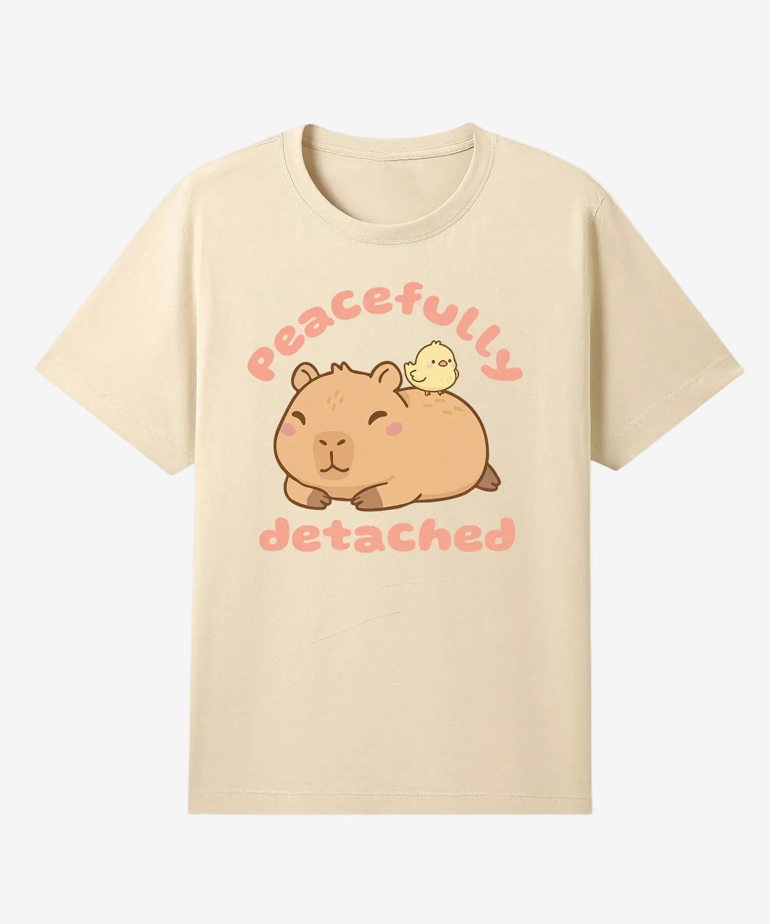 Beige t-shirt with a cartoon capybara and chick design and text 'Peacefully detached' on a white background.